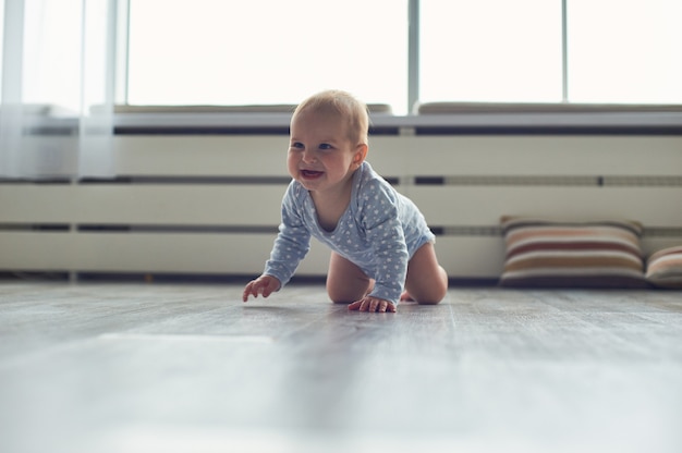 Pequeño bebé gateando en el piso en casa