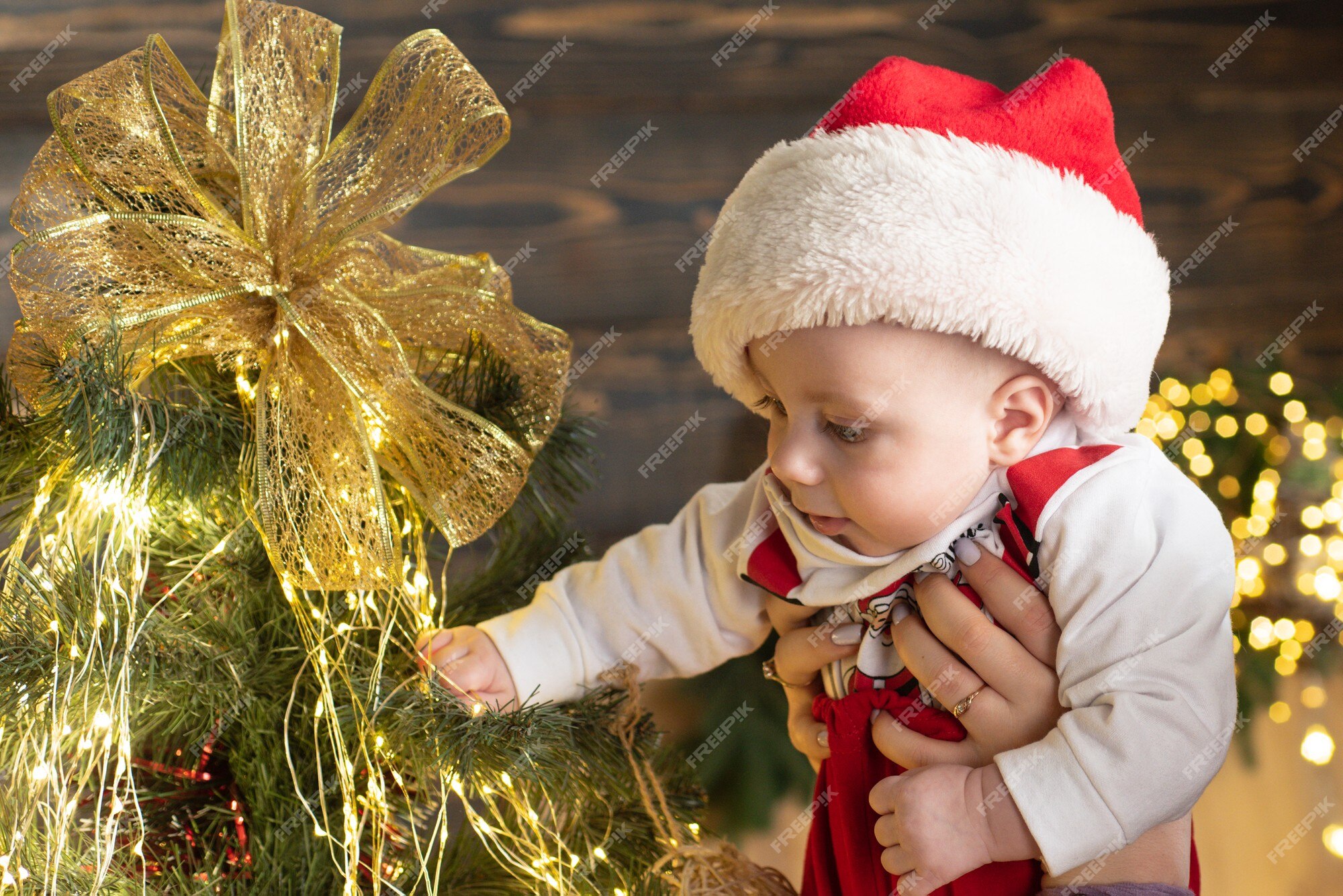bebé lindo en el árbol de navidad. cara divertida del niño de 1 año de cerca. retrato de bebé con ropa de santa. | Foto Premium