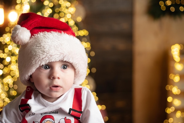 Pequeño bebé lindo en el árbol de Navidad.