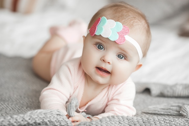 Foto pequeño bebé lindo en casa en el dormitorio. un bebé en el interior. retrato de niño de sexto mes. adorable niña linda.