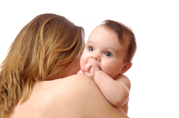 Pequeño bebé lindo que sonríe en el hombro de las madres