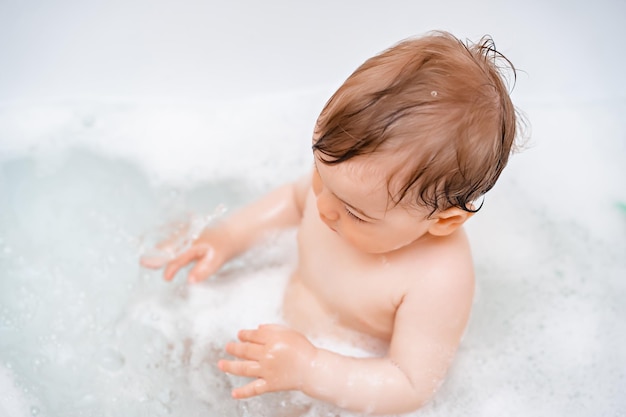 Foto pequeño bebé lindo tomar un baño y jugar con burbujas de espuma y juguete