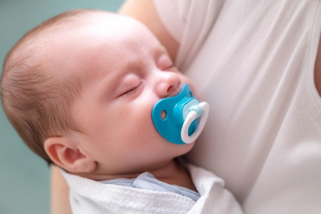 Pequeño bebé recién nacido durmiendo con un maniquí en las manos de la madre en casa, mamá pone al bebé a dormir