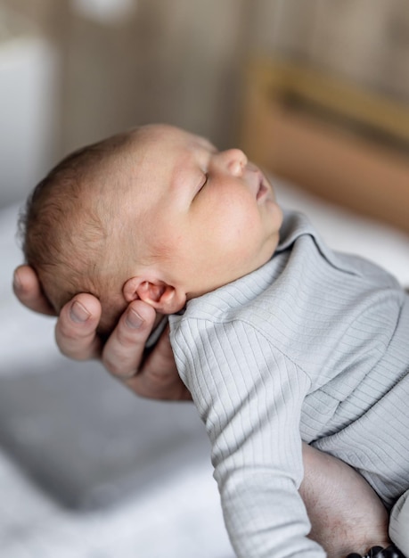 Pequeño bebé recién nacido en las manos sosteniendo el brazo de un niño de pocos meses