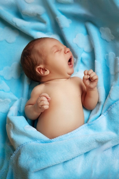 Foto pequeño bebé recién nacido en una manta azul