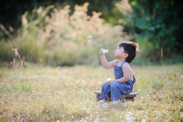 pequeño bebé soplando pompas de jabón en el parque de otoño