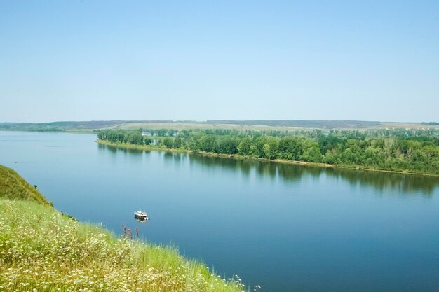 Pequeño bote en el río azul y la orilla verde