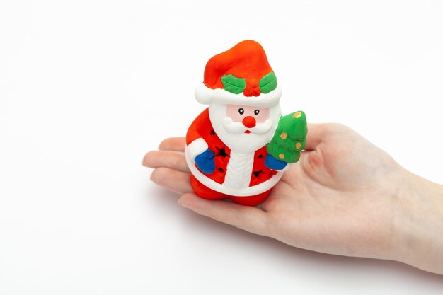 Pequeno brinquedo artesanal de Papai Noel na mão da mulher em um fundo branco. conceito de Natal e ano novo. isolado no fundo branco para design