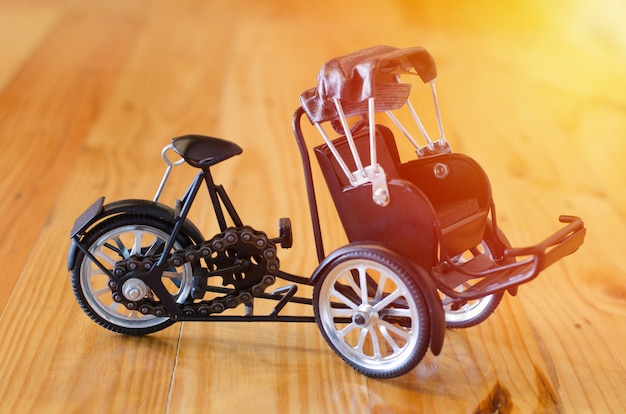 Foto pequeno brinquedo de madeira, modelo de táxi triciclo de três rodas em fundo de madeira
