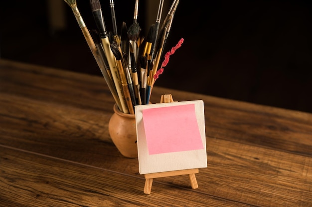 Un pequeño caballete con un trozo de papel y un pincel sobre la mesa.