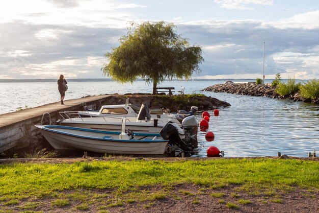 Foto pequeno cais com barcos e uma menina de costas olhando para o mar