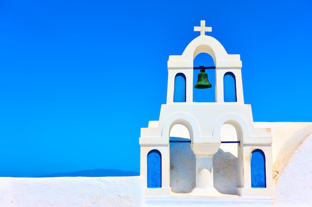 Pequeno campanário branco na cidade de Oia em Santorini contra o céu azul, Grécia