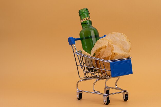 Pequeno carrinho de compras com batatas fritas e uma garrafa de cerveja