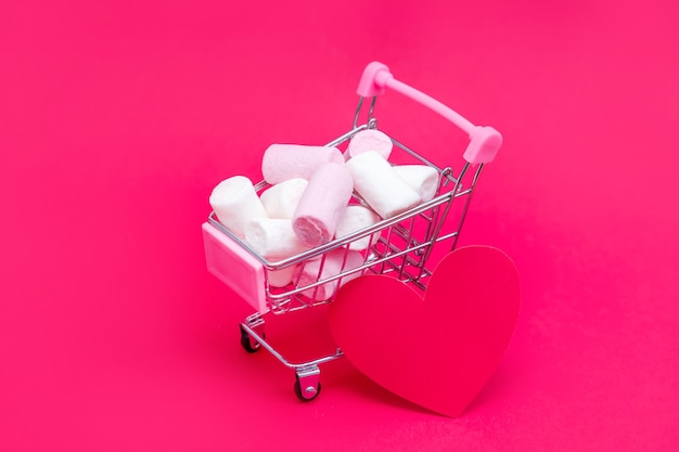 Pequeno carrinho de supermercado cheio de doces de marshmallow. Dê presentes com amor no Dia dos Namorados e