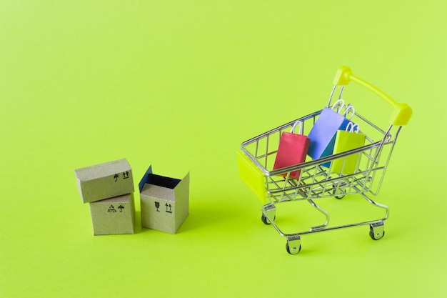 Un pequeño carrito de la compra con cajas y bolsas sobre un fondo verde