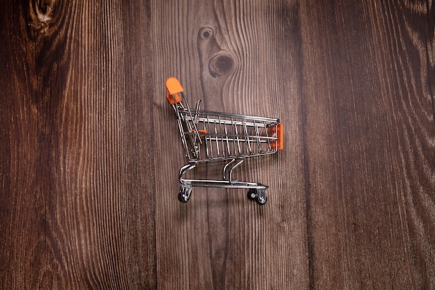 Pequeño carrito de compras sobre fondo de madera. Carrito de compras.