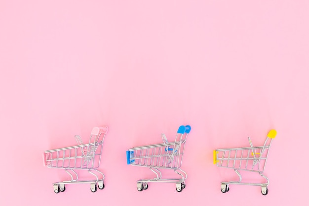 Pequeño carrito de compras sobre fondo rosa