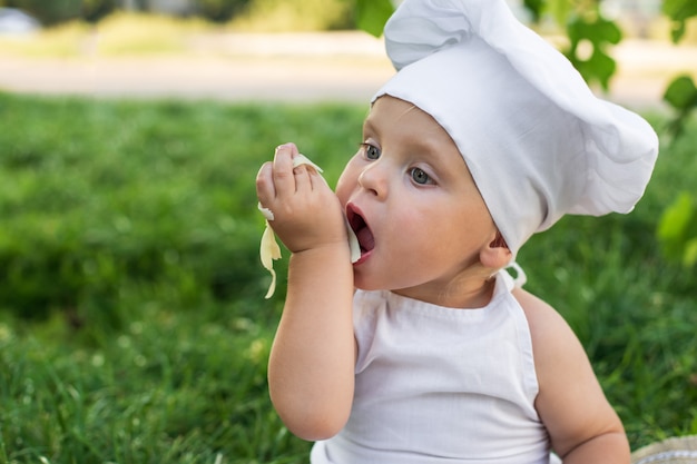 Pequeno chef cozinha e come macarrão em um piquenique ao ar livre