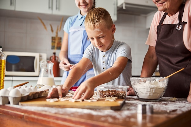 Pequeno chef entusiasmado fazendo biscoitos com a ajuda de sua família