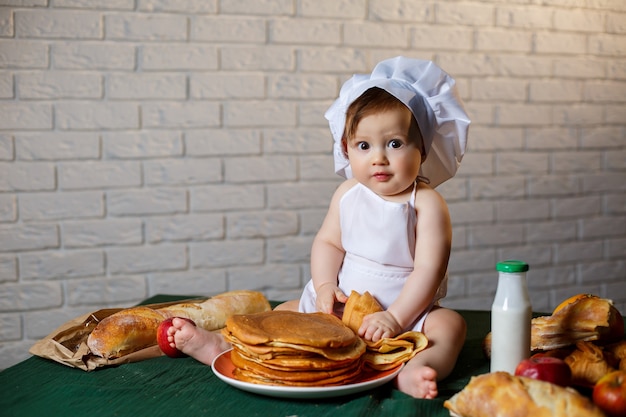 Pequeño chef. Niño disfrazado de chef con pasteles, bollos, pan