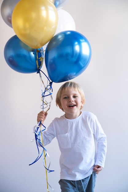 pequeño chico rubio sonriente con globos celebración de cumpleaños