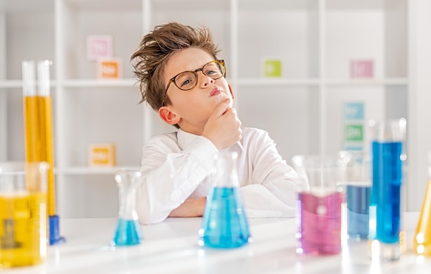 Pequeño científico pensativo en el laboratorio de química