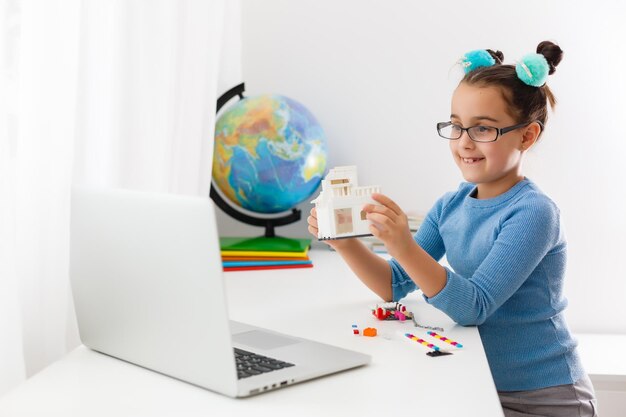 Pequeño científico que trabaja en un nuevo proyecto, niña estudiando robótica en una computadora portátil en línea