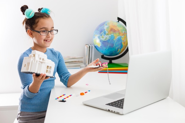 Pequeño científico que trabaja en un nuevo proyecto, niña estudiando robótica en una computadora portátil en línea