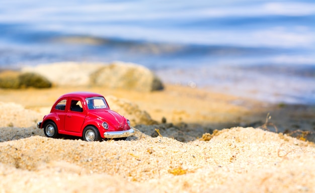 Pequeño coche rojo en la playa de arena