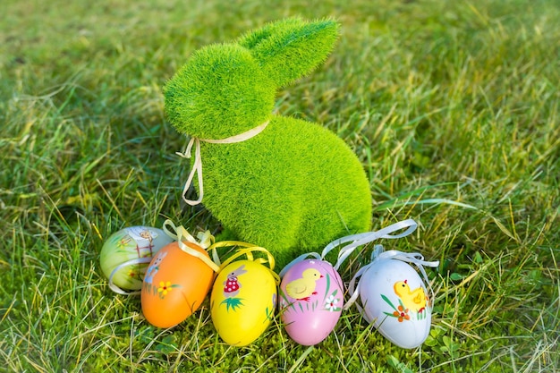 Pequeno coelho bebê e ovos de Páscoa na fresca paisagem verde da primavera