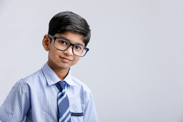 Pequeño colegial indio / asiático lindo que lleva uniforme y gafas