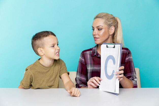 Pequeño colegial joven que hace la tarea con la madre, cooperación en la familia, paternidad.