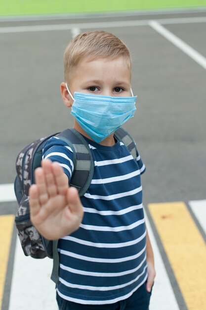 Un pequeño colegial con máscara durante un brote del virus corona