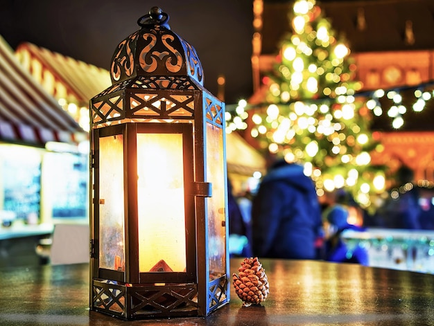 Pequeno cone perto da lanterna de vela brilhante nas mesas do mercado de Natal em Riga, Letônia. O mercado geralmente ocorre a partir do final de novembro até o início de janeiro.