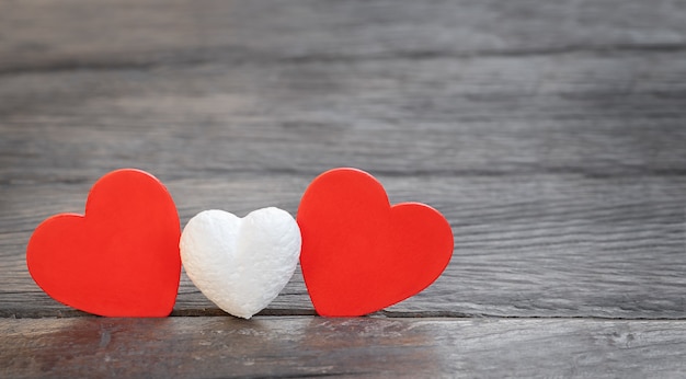 Pequeño corazón blanco y dos corazones rojos sobre un fondo de madera. concepto de familia