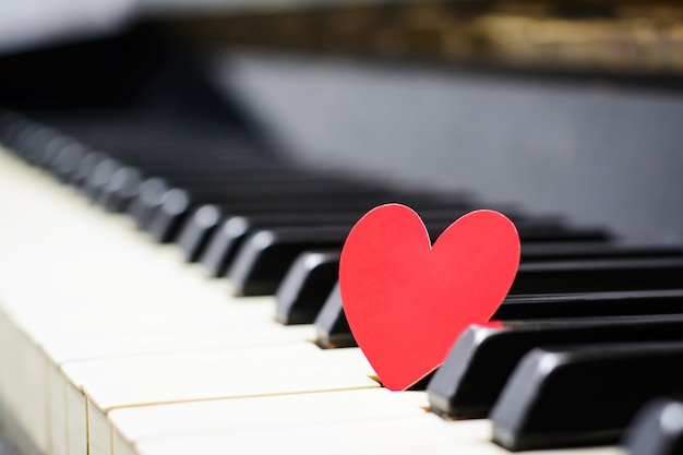 Pequeño corazón de papel rojo en las teclas del piano