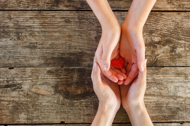 El pequeño corazón rojo está en manos de hombres y mujeres, el concepto de amor y romance.