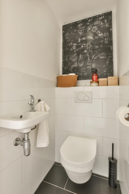 Un pequeño cuarto de baño blanco con inodoro y lavabo.