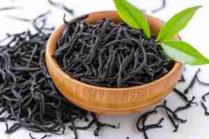 Foto un pequeño cuenco de madera con hojas de té y una pequeña hoja verde en él