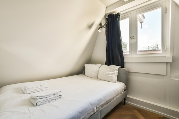 Un pequeño dormitorio con una cama y dos ventanas.