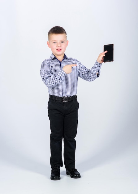 Pequeño empresario. Crianza y desarrollo. Teléfono móvil de ropa formal de niño pequeño. Un chico lindo tiene un smartphone. Tecnología móvil. Descargar aplicación. Comunicación móvil. Gadget moderno.