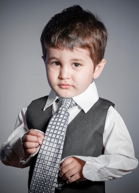 pequeno empresário, menino de cabelos castanhos vestido de terno e gravata com rostos e expressões engraçadas