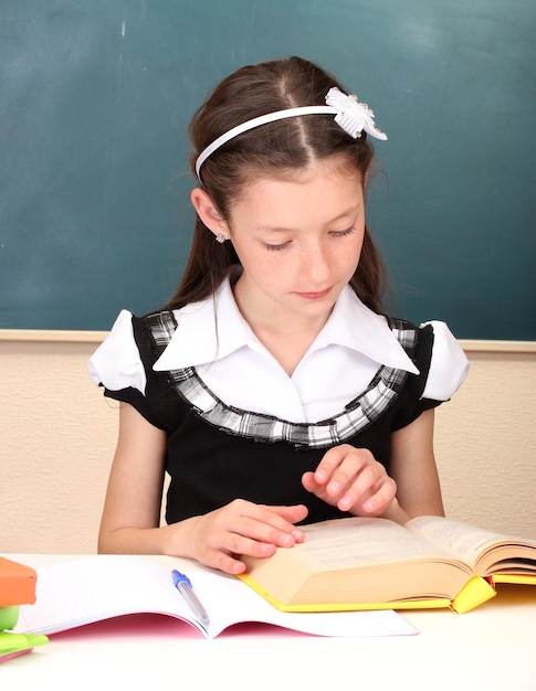 Pequeño escolar en el aula escribe en un cuaderno