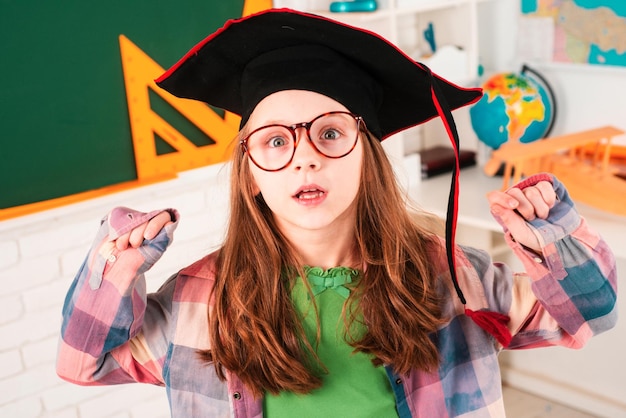 Pequeño estudiante emocionado en la escuela secundaria de posgrado o gorra universitaria