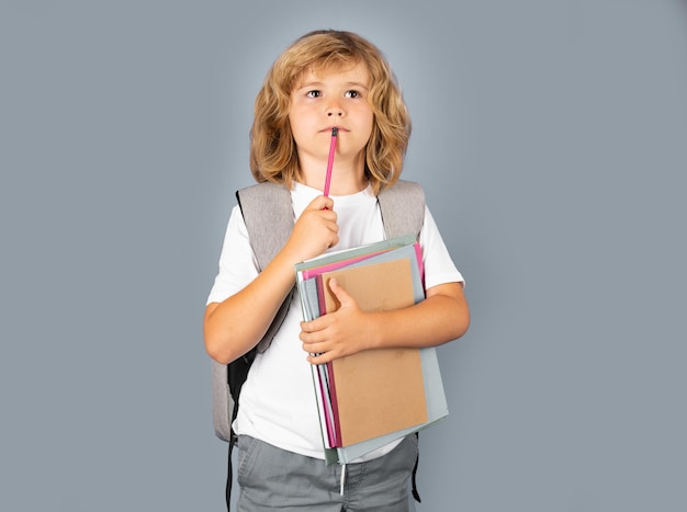 Pequeño estudiante de escuela sostiene libros concepto de educación para niños niño en uniforme escolar pensando en niño pensativo