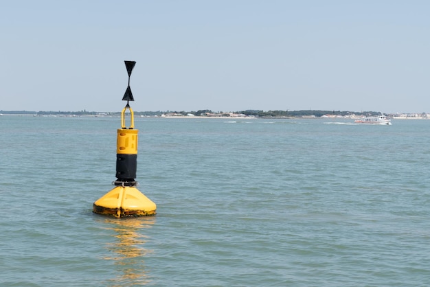 Foto pequeño faro boya negra y amarilla en el agua de mar para la señal del barco