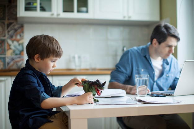 Pequeno filho perturbador trabalhando pai freelancer