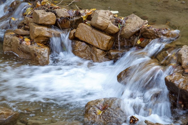 Foto pequeno fluxo de água flui através de uma barreira de grandes pedras