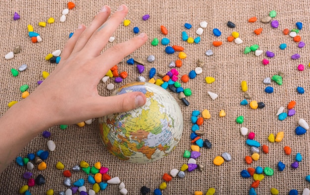 Pequeño globo terráqueo en medio de guijarros de colores