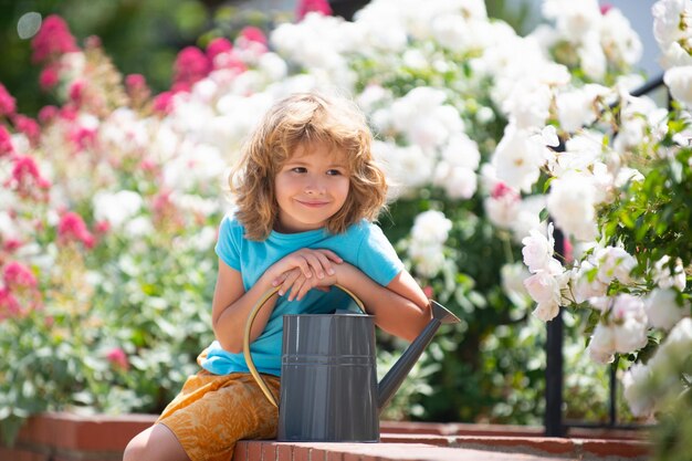 Pequeño granjero con regadera en el jardín plantando flores